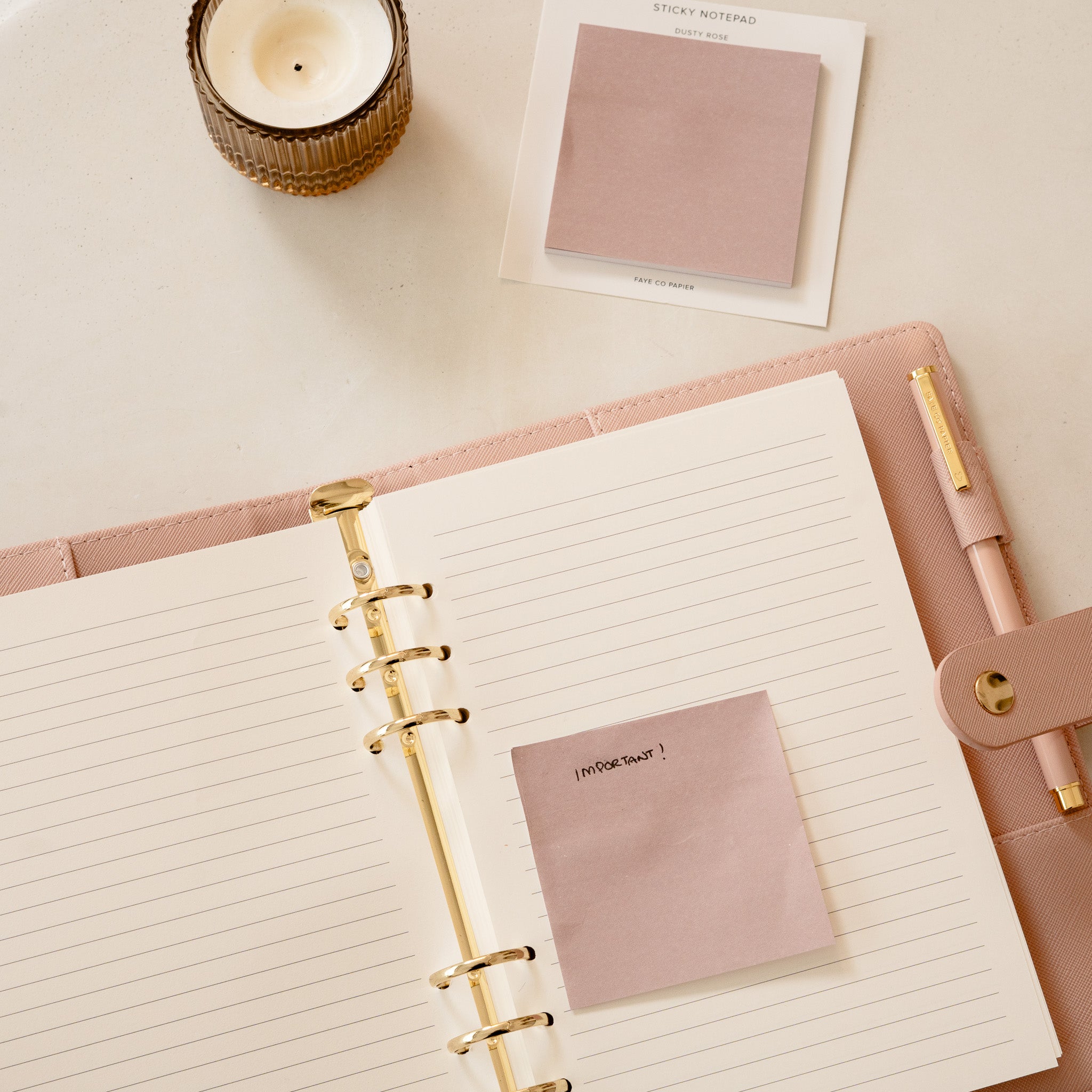 Open planner with pink sticky notes and pen on a light surface