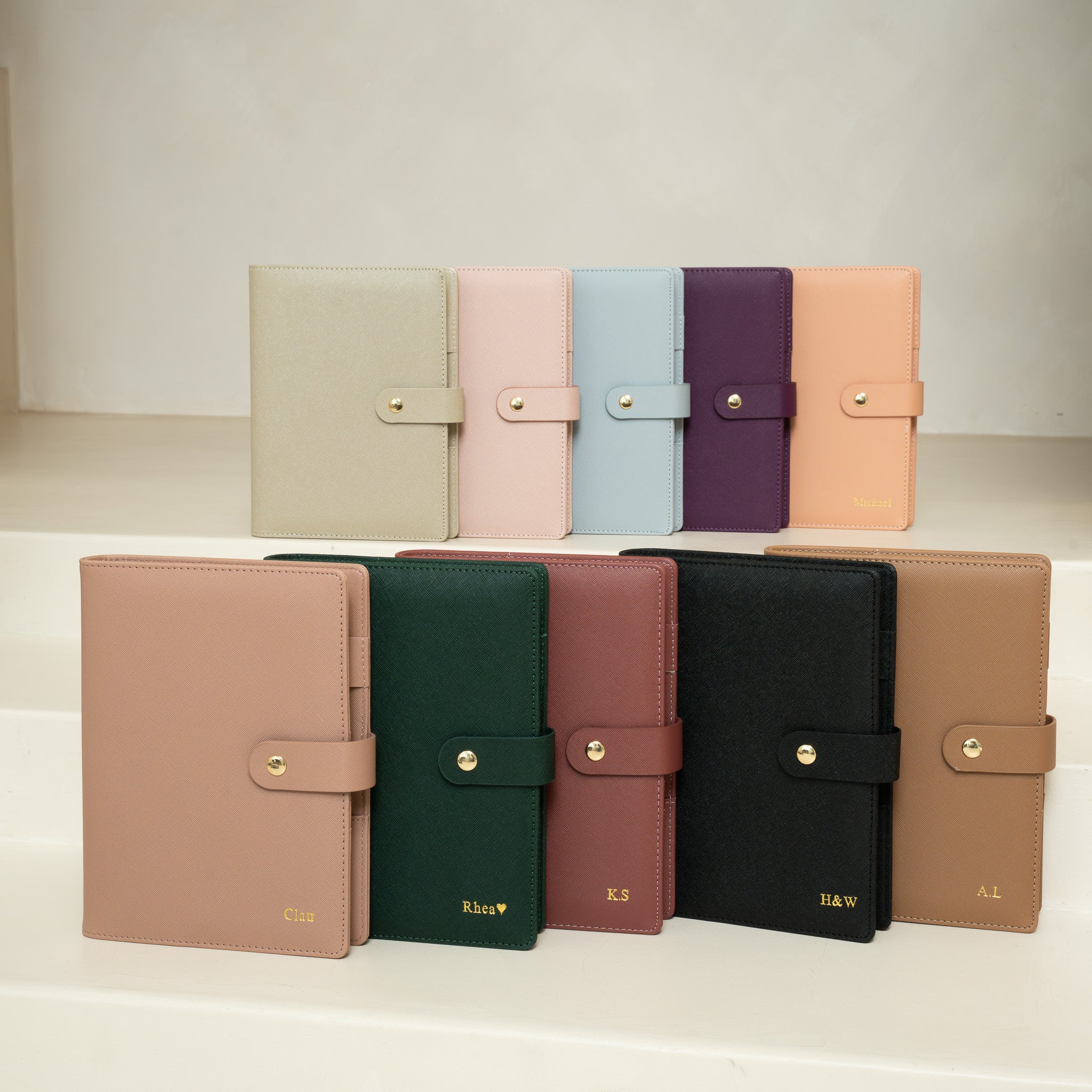 Eight A5 ring binder refillable planner covers made of vegan leather. Colour  covers in light beige, pink, light blue, purple, and peach, dusty pink, forest green, burgundy, black, and tan.
